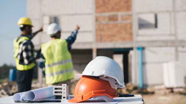 Structural engineer and architect working with blueprints discuss at the outdoors construction site.